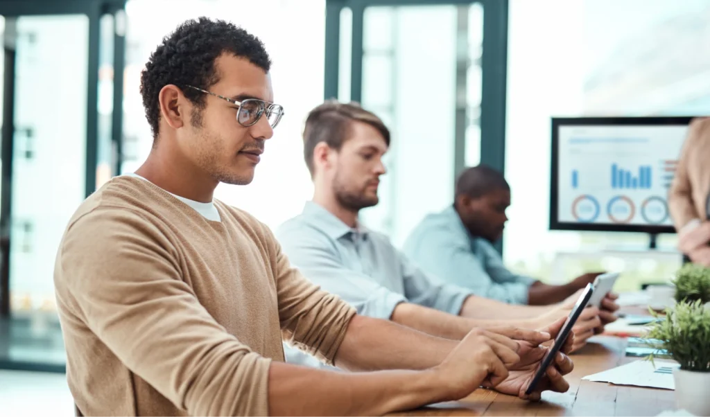 Photo of several men working in office environment on tablet devices.