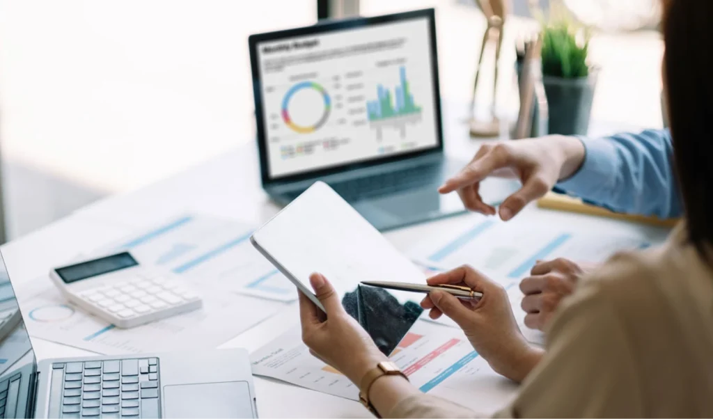 Photo of man looking at computer monitors. Photo of business professionals looking at data on tablet and laptop.